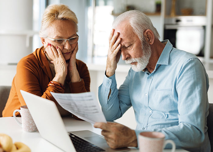 worried senior couple looking at bills